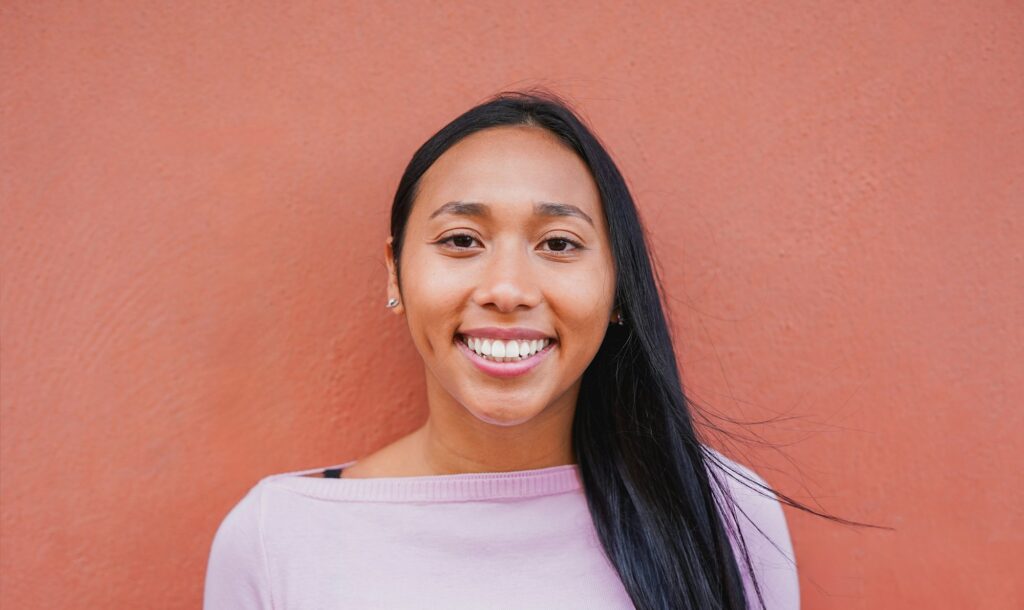 Portrait of native american woman smiling on camera with city wall in background